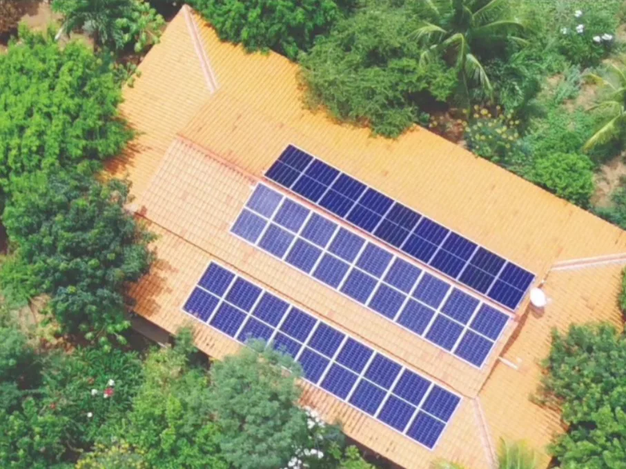 Vista aérea de casa de telha cerâmica cercada de árvores, com 27 módulos fotovoltaicos no telhado, em Floresta-PE